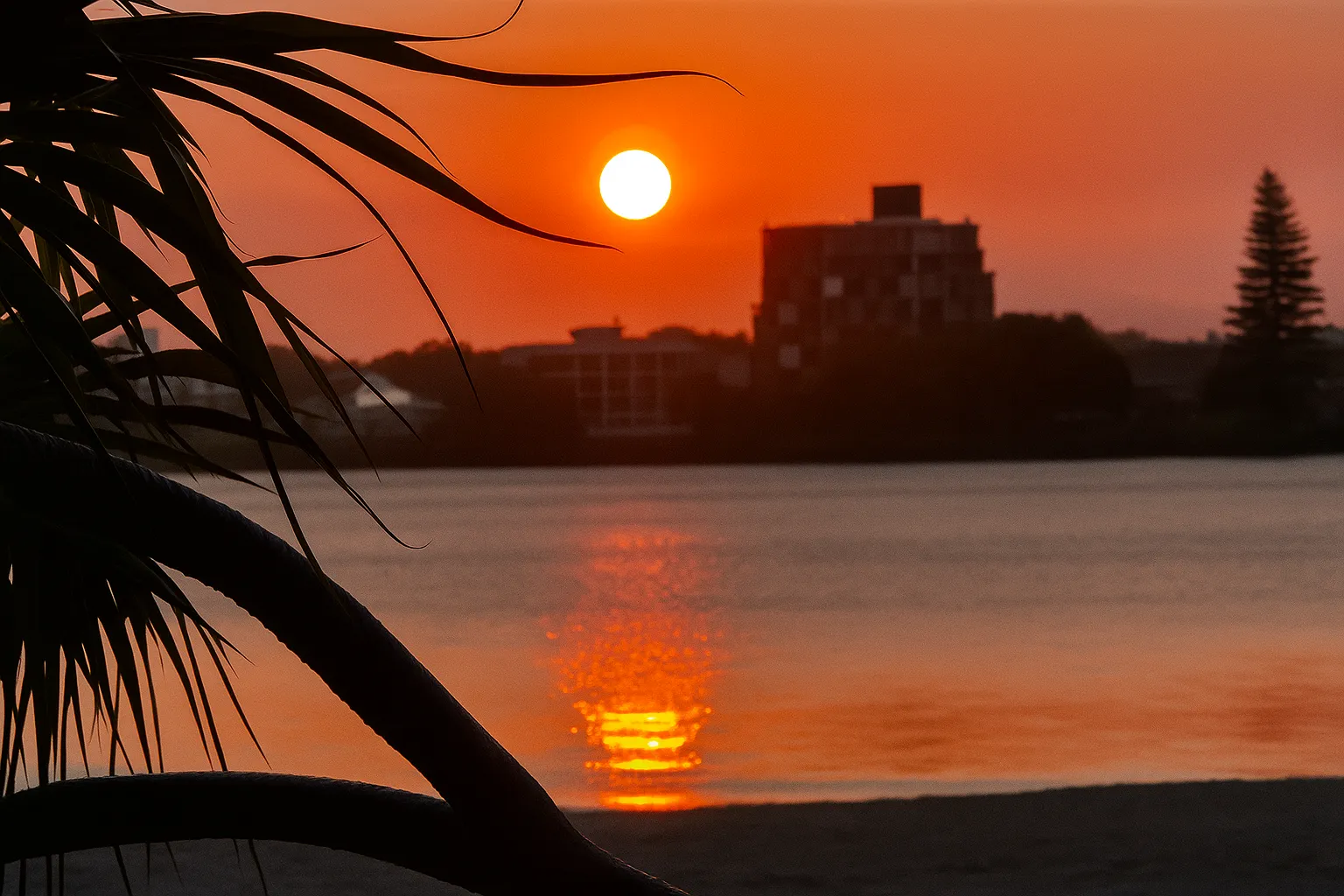 Happy Valley sunset reflected over calm water in Caloundra